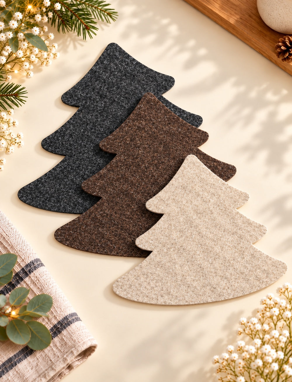 VIOLAN Filzuntersetzer in Tannenbaumform aus 4 mm meliertem Filz in Anthrazit, Dunkelbraun und Natur auf einem weihnachtlich dekorierten Holztisch.
